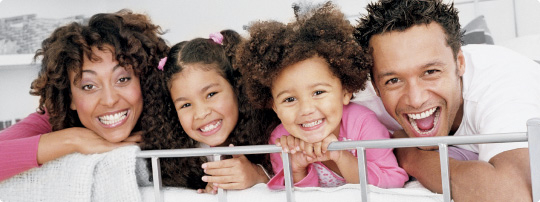 Happy African American family smiles while cuddled together on a bed