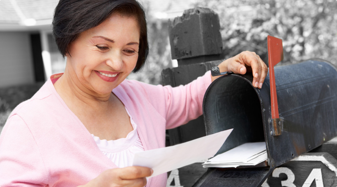 Woman smiles as she reads a piece of mail from a dental marketing company